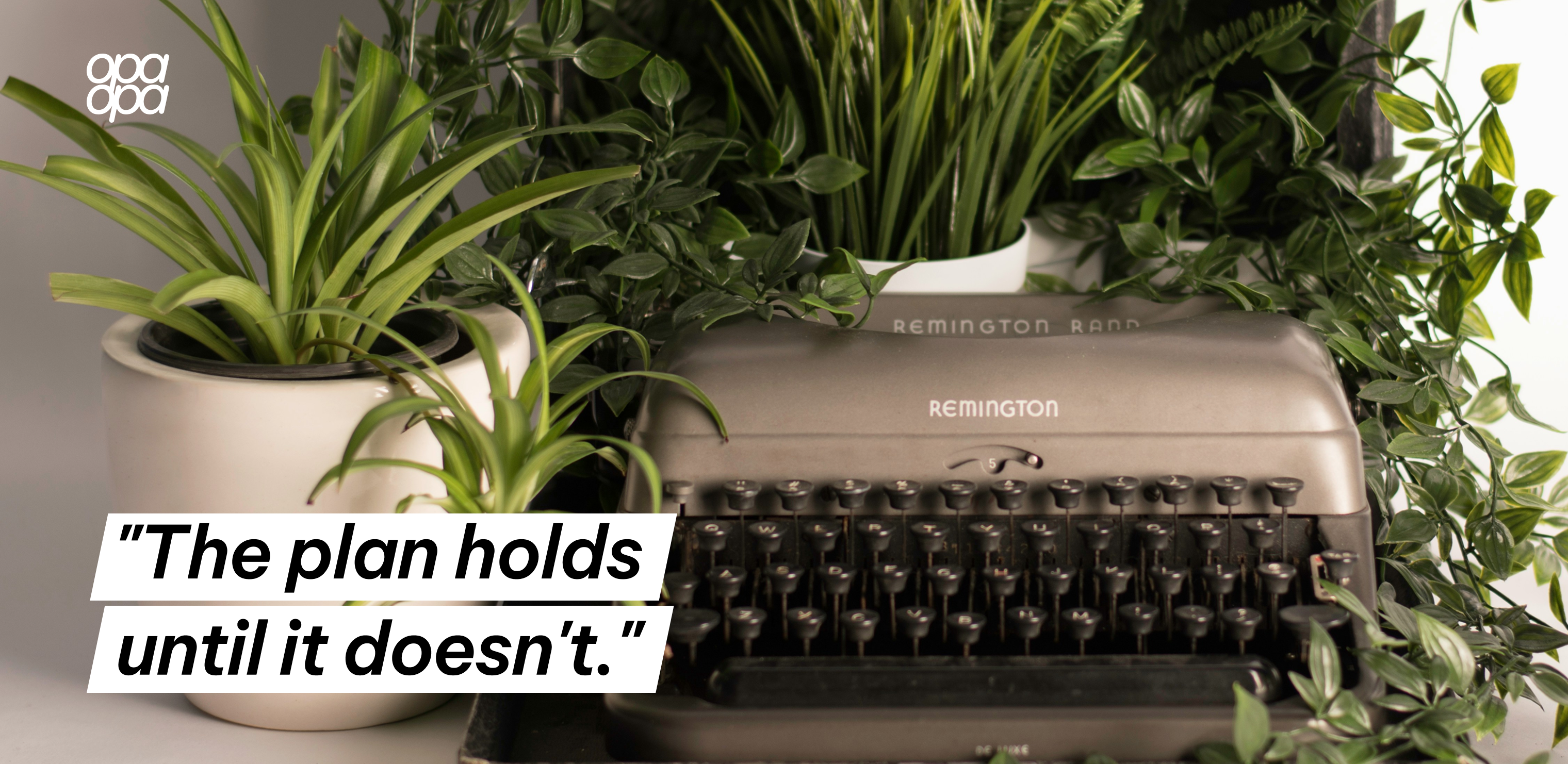 A vintage Remington typewriter surrounded by green plants